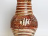 a brown vase that is sitting on a white surface