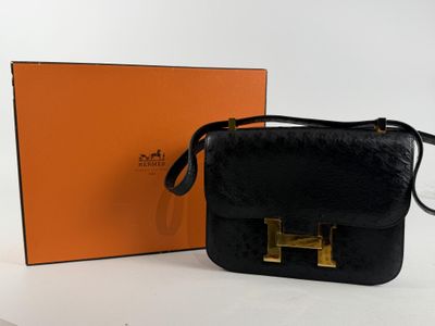 sac à main en cuir noir avec des finitions dorées et un coffret orange