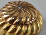 a close up of a gold plated object on a white surface