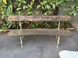 un banc en bois posé devant un buisson