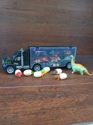 a toy truck with dinosaurs and eggs in front of it