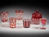 plusieurs vases et verres en verre rouge posés sur une surface blanche