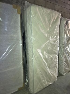 many mattresses lined up in a warehouse with plastic covering