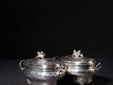 a pair of silver dishes with handles and handles on a black surface