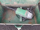 a green box with a tool in it on the ground