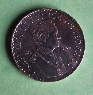 a close up of a coin on a green surface with a green background