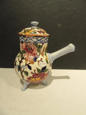 a small ceramic teapot with a handle on a table