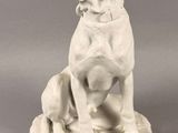 a white statue of a dog sitting on a rock