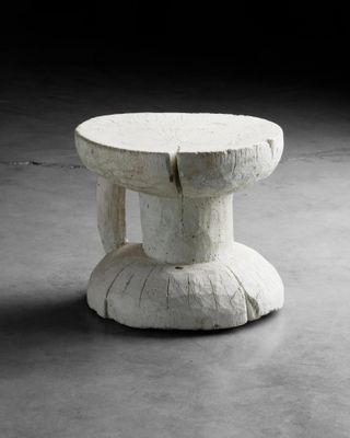 une petite table blanche avec un piètement en bois posée sur un sol en béton