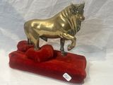 a gold statue of a bull on a red cushion