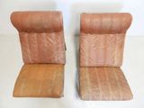 pair of brown leather chairs sitting next to each other on a white floor