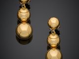 a pair of gold earrings on a black surface