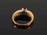 a gold ring with a sapphire stone on a black surface