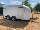 the trailer is parked on the grass in front of a building