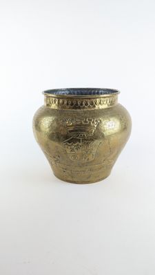 un vase en or posé sur une surface blanche