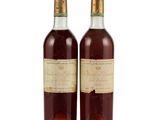 two bottles of wine sitting next to each other on a white surface