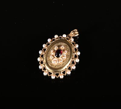 un gros plan sur un pendentif en or orné de perles et d'une pierre rouge
