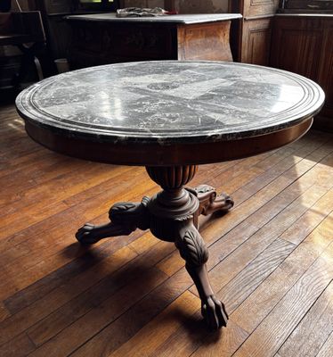 une table au plateau en marbre posée sur un parquet, dans une pièce