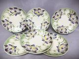 quatre assiettes ornées de fleurs violettes et jaunes, posées sur une table