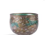 a brown bowl with green designs on it on a white surface