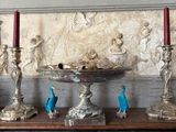 three silver candles sitting on a table in front of a wall