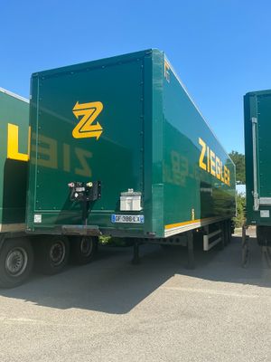 two green semi trailers parked in a parking lot