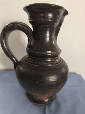un vase noir posé sur un tissu bleu, sur une table
