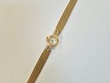 gros plan d'une montre en or sur une surface blanche