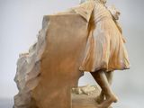 statue of a woman leaning on a rock with her back to the ground