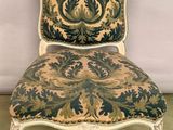 une vieille chaise dont le dossier est recouvert d'un tissu bleu et vert