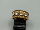 une image représentant une bague en or et diamants posée sur un morceau de bois noir