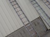 several ladders are leaning against a wall in front of a building