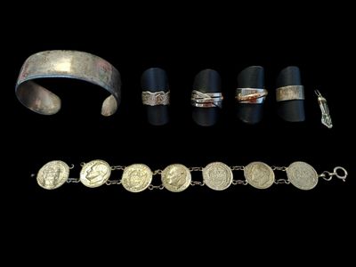 several silver bracelets and rings are shown on a black background