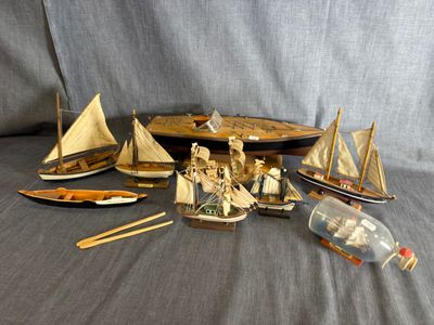 beaucoup de petits bateaux en bois et une bouteille posée sur une table