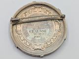 a close up of a silver brooch with a pin on it