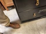 a man standing in front of a drawer with a pair of shoes on it