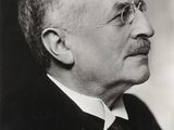 une vieille photo en noir et blanc d'un homme à lunettes et moustachu