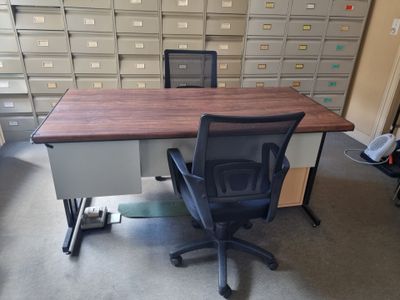 un bureau avec une chaise devant, dans une pièce remplie d'armoires de classement