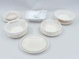 several white plastic bowls and plates are arranged on a table