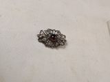 a silver brooch with a red stone in it