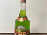 a bottle of green liquid sitting on a wooden table