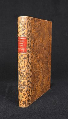 a brown book with a red cover sitting on top of a black surface