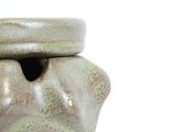 a ceramic jar with a lid on a white surface