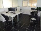 a desk with two computers and a chair in the room