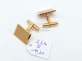 two pairs of gold cufflinks with a price tag on a white surface