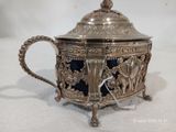 une théière en argent contenant un verre bleu