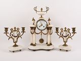 trois bougies et une horloge posées sur une table
