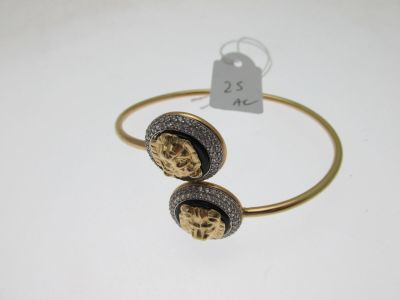 a gold bracelet with two skulls on it and a price tag
