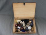 a wooden box filled with assorted jewelry on a gray surface