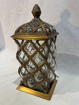 brass and glass candle holder with a bird on top of it